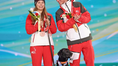 Illustration : Une skieuse de fond offre une médaille à son chien guide pour le remercier de l’avoir aidé à monter sur le podium 